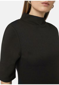 Haut noir à manches courtes avec un col montant. Fabriqué en matériau doux, présentant une texture lisse et une silhouette ajustée. Pas de motifs notables.