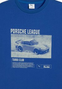 T-shirt en coton bleu avec un imprimé graphique d'une voiture Porsche vintage, avec le texte "Porsche League" et "Turbo Club" en blanc et bleu clair.