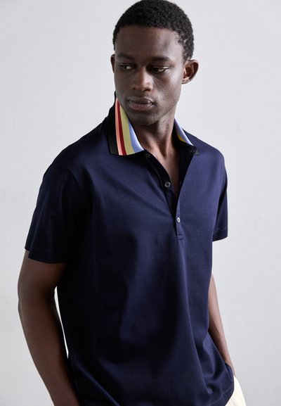Polo-shirt marine avec un col à boutons, featuring un col rayé en rouge, jaune et noir. Tissu lisse et manches courtes.