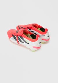 Ζευγάρι φωτεινών κοραλλί και λευκών παπουτσιών ποδοσφαίρου Adidas Predator με μαύρ ες ρίγες και κοντά καρφιά, εμφανιζόμενα από πίσω πλάγια γωνία.
