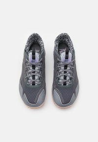 Šedé sportovní boty s texturovaným svrškem, síťovanými prvky, reflexními detaily a podšívkou s leopardím vzorem. Obsahují ploché tkaničky a gumové podrážky.