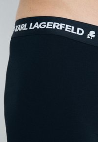 Juoda vyrų bokso kelnaitės su minkšta tekstūra, su balta elastine juosta, kurioje pavaizduota "KARL LAGERFELD" logotipas ir ikonos detalė.