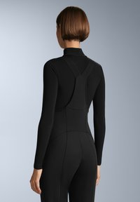 Černý bodysuit s dlouhým rukávem a vysokým límcem, který má přiléhavý střih a prošívané detaily na zádech a po stranách. Hladká textura.