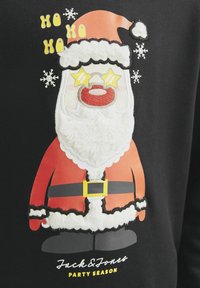 Le Père Noël avec des lunettes en forme d’étoile et une barbe duveteuse sur un tissu noir, entouré de flocons de neige et du texte « Ho Ho Ho », avec « Jack & Jones Party Season » en dessous.