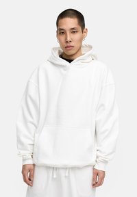 Weißer Kapuzenpullover mit vorderer Tasche, lockerer Passform und gerippten Bündchen. Aus weichem Stoff gefertigt, mit einer Kordelzugkapuze und minimalistischem Design.