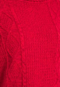 Rode gebreide trui met een textuurpatroon van verhoogde ruiten en vlechtontwerpen. Dichte, warme stof met een geribbelde kraag.