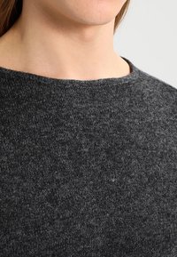 Dunkelgrauer Strickpullover mit Rundhalsausschnitt, der aus einem weichen, strukturierten Stoff besteht und subtile Farbvariationen aufweist.