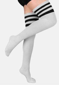 Oberschenkelhohe Socken in Weiß mit schwarzen horizontalen Streifen am oberen Rand. Glattes Strickgewebe, taillierter Schnitt und geschlossener Zehenbereich.