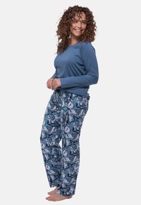 Maglietta azzurro chiaro a maniche lunghe abbinata a pantaloni a fantasia floreale nei toni del blu e del bianco. Tessuto morbido con vestibilità rilassata e design comodo.