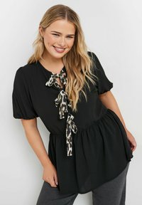 Blusa nera con maniche corte e a palloncino. Presenta un collo a chiave con lacci a stampa leopardata. Vita elastica, orlo fluente. Tessuto morbido.