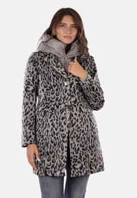 Abrigo de estampado de leopardo gris y negro con dos botones, bolsillos y una chaqueta interior gris desmontable con cuello alto y cremallera.