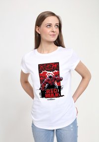 Bílý bavlněný tričko s potiskem v komiksovém stylu zobrazuje Červeného Hulka v červené a černé barvě na pozadí s červenými skvrnami, s textem "ČERVENÝ HULK" pod ním.