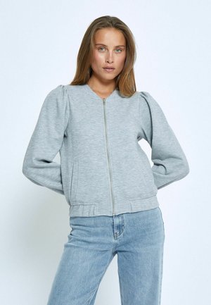 Gray zip-up sweatshirt made of soft fabric, featuring puffed sleeves, ribbed hem, and side pockets. Paired with light blue jeans.