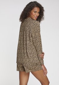 Loungewearset met luipaardprint in tan en bruin, bestaande uit een top met lange mouwen en bijpassende shorts, gemaakt van lichtgewicht stof.