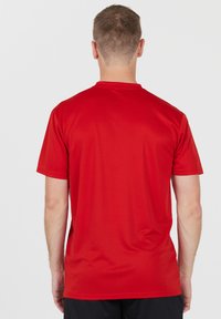 Rød t-shirt med korte ærmer, glat tekstur, rund halsudskæring og en afslappet pasform. Ingen synlige mønstre eller grafik; enkel design.