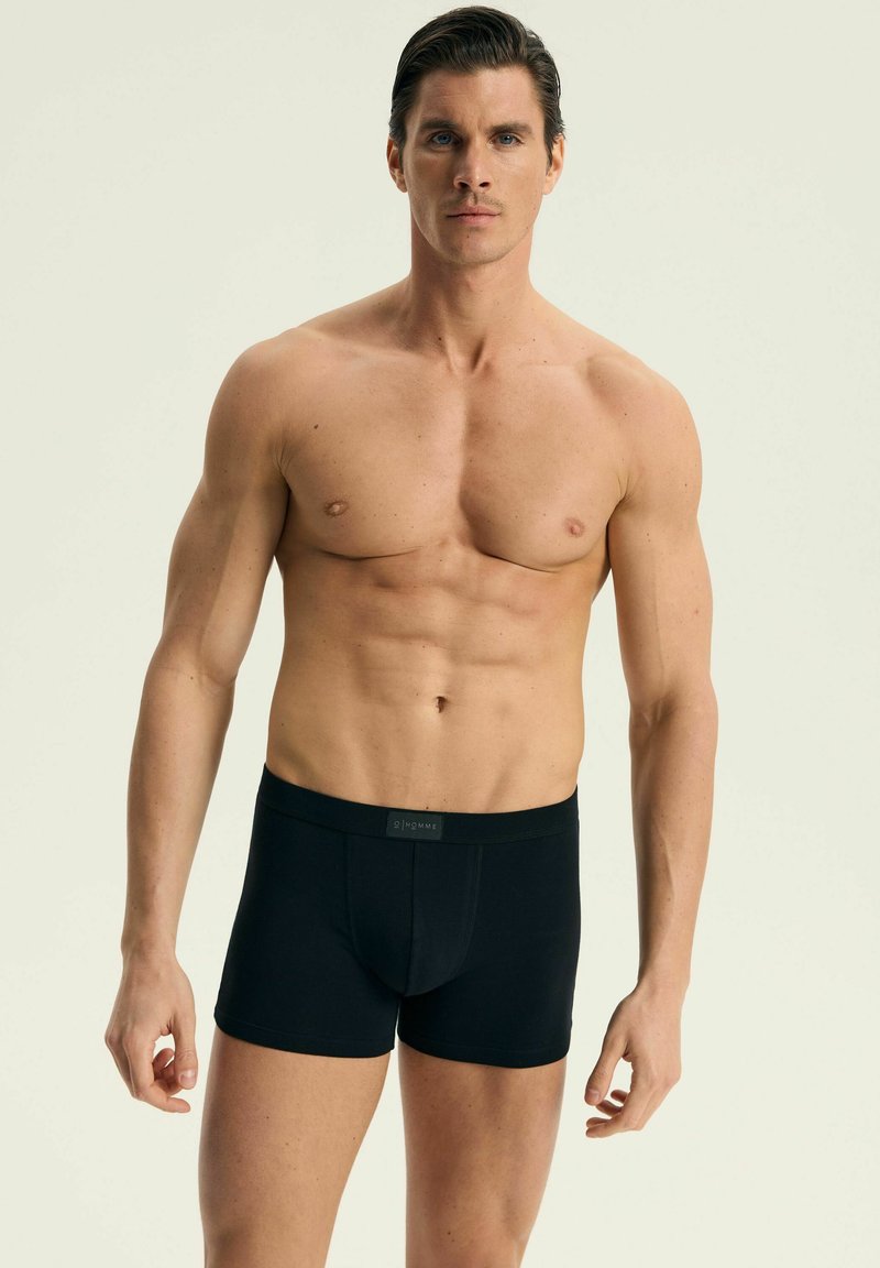 Czarne bokserki wykonane z elastycznego materiału, z logo na pasku, dopasowany krój, średni stan i gładka tekstura.