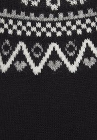 Schwarzer Strickwollstoff mit einem weißen geometrischen Muster, das Zickzack- und runde Motive zeigt und unterschiedliche Texturen und Sticharten präsentiert.