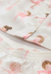 Ensemble de pyjama en coton de couleur beige clair orné d'illustrations rose de danseuses de ballet et doté d'une taille élastique pour le confort.