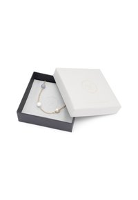 Guld kædearmbånd med lysegrå, hvide og blå perler, præsenteret i en tofarvet æske med et struktureret hvidt låg og grå bund.