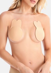 Beige lepící prsní kryty ve tvaru kruhů se zaoblenými okraji, s hladkým povrchem pro diskrétní a bezproblémové nošení pod oblečením.