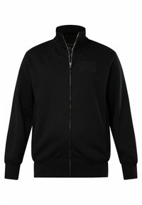 Giacca nera con zip e colletto alto, tessuto texturizzato e scritte in rilievo sul lato sinistro del petto. Polsini e orlo a costine. Design semplice e pulito.