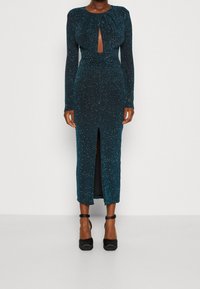 Türkises Langarmkleid mit einem Ausschnitt in Form eines Schlüssellochs, strukturiert mit Glitzer. Verfügt über einen Oberschenkel-spitzen Schlitz und ein figurbetontes Design, kombiniert mit schwarzen High Heels.