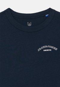 Μπλε ναυτικό T-shirt με στρογγυλή λαιμόκοψη, με μικρό λευκό κείμενο "JACK & JONES ARCHIVE" στο στήθος και ένα μικρό λογότυπο προσώπου σκύλου μέσα στον γιακά.