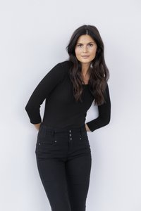 Crni top s dugim rukavima i okruglim izrezom, upareni s crnim trapericama visokog struka s kopčanjem na gumbe. Glatka, rastezljiva tkanina.