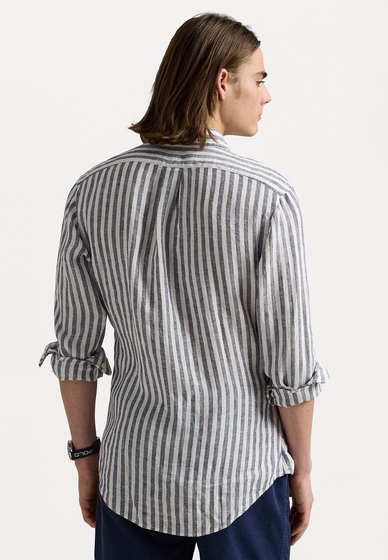 Gestreept shirt in lichtgrijs en marineblauw, gemaakt van lichtgewicht stof. Heeft opgerolde mouwen en een gebogen zoom. Achteraanzicht weergegeven.