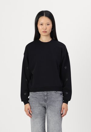 Juodas sportinis džemperis su ilgomis rankovėmis, apvalia iškirpte ir širdelės formos akcentais ant rankovių. Turi laisvą siluetą ir minkštą tekstūrą.