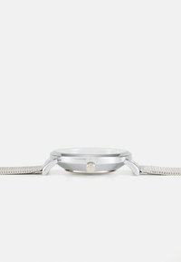 Silver-tone watch featuring a round case, glass face, and a textured mesh strap. Includes a crown for adjustment. Minimalist design.