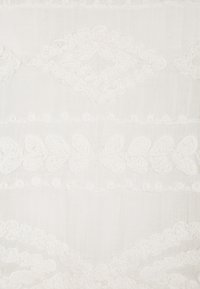 Bílá tkanina s jemnými krajkovými vzory, obsahující diamantové tvary a srdíčkové motivy, což jí dává texturovaný a delikátní vzhled.