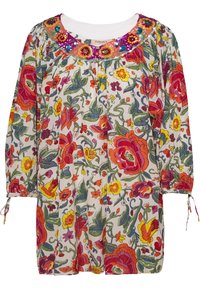 Květinová tunika s jemným bílým podkladem, která má barevné vzory červených, oranžových a žlutých květin, kulatý výstřih se sequinovým zdobením a elastické manžety.