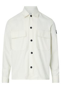 Giacca button-up beige chiaro in cotone, con due tasche sul petto e bottoni neri. Include una patch con logo laterale e maniche lunghe.