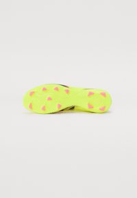 Soccer cleat sole in bright yellow with textured pattern, featuring pink triangular studs for traction. Smooth, durable material.