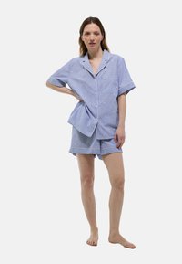 Un ensemble de pyjama court rayé bleu et blanc comprenant une chemise à manches courtes avec boutons et un short assorti, conçu avec une coupe décontractée et un col.