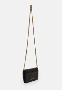 Black quilted rectangular purse with gold chain strap and small gold brand plaque on front, shown hanging against white background.