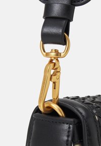 Correa de cuero negro conectada a un bolso de cuero trenzado negro con un cierre de metal dorado grabado "KARL LAGERFELD".
