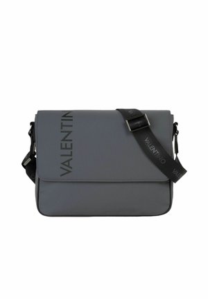 Sac messager gris Valentino avec une sangle noire réglable et un logo noir imprimé verticalement sur le rabat et la sangle.