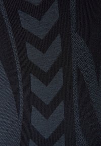 Czarna teksturowana tkanina z wzorem chevron w różnych odcieniach ciemnoszarego, prezentująca gładką, prążkowaną powierzchnię.