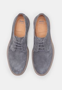 Scarpe in suede grigio con punta arrotondata, texture liscia e dettagli cuciti. Presentano un design con lacci e suola in gomma marrone.