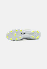 Semelle de chaussure de sport Nike avec une semelle blanche, des accents gris, une texture circulaire, un logo noir et des pointes jaunes vives pour l'adhérence.