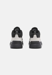 Černé a šedé tenisky s texturovaným svrškem, polstrovaným límcem a silnou bílou mezipodešví s gumovou podrážkou. Šněrování vzadu.