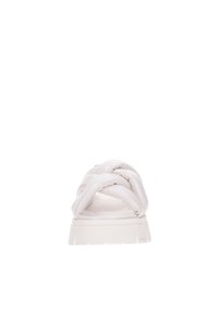 Sandalia plana blanca con diseño de tiras trenzadas, textura suave, suela de goma plana y estética minimalista.