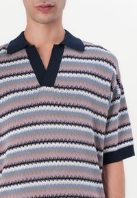 Kurzärmliges Poloshirt aus gestreiftem Strick mit rosa, blauen und weißen Mustern. Verfügt über einen marineblauen Kragen und ein V-Ausschnitt-Design. Weiche Textur.