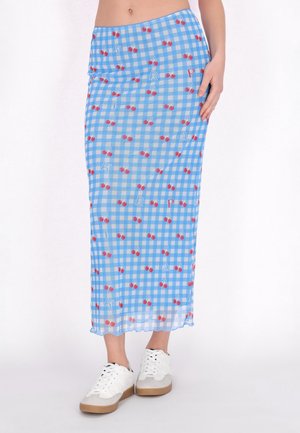 Blåternet maxi-nederdel med kirsebærprint, letvægtsstof og bølget kant, parret med hvide sneakers.