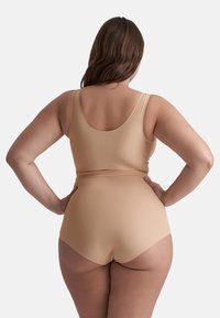 Costume da bagno a due pezzi color nude, con top a scollo profondo e slip a vita media. Tessuto morbido e elastico con cuciture minime e design aderente.