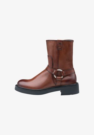 Brun læder ankelstøvle med rund tå, flad sål, dekorativ rem med en metalring og kontrasterende sorte syninger. Gummisål.