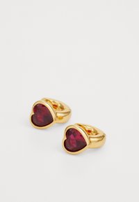 Pendientes en forma de corazón chapados en oro, con piedras preciosas de color rojo intenso, curvas suaves y un acabado pulido con engastes de garra visibles.