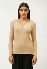 Beige gestreiftes Langarmoberteil mit einem gewellten V-Ausschnitt und drei Knöpfen vorne. Sanfte Textur mit leichten Schimmerakzenten.